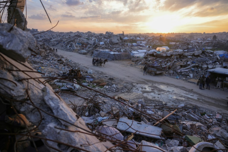 Des Palestiniens traversent à bord d'une charette une route au milieu des décombres à Beit Lahia, dans le nord de la bande de Gaza, le 4 mars 2025 ( AFP / Bashar TALEB )